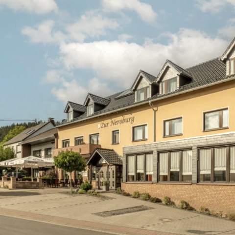 Die gelbe Hausfassade des Hotels mit angrenzender Terrasse