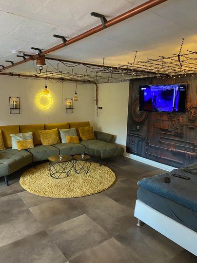 Wohn-Schlafzi. mit Couch und Bett, gefliester Boden, runder Teppich vor dem Sofa.