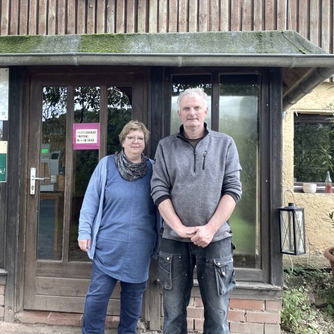 Ein Mann und eine Frau stehen vor einem Geb&auml;ude und l&auml;cheln in die Kamera.