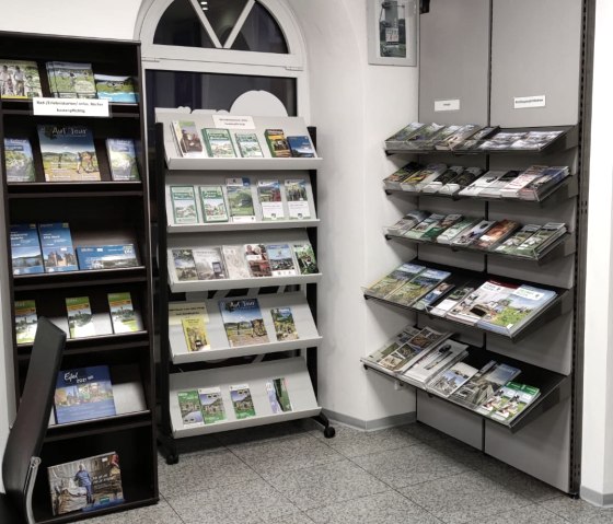 Interior of the Hillesheim Tourist Information Centre with several shelves displaying tourist brochures and shelves with regional souvenirs.