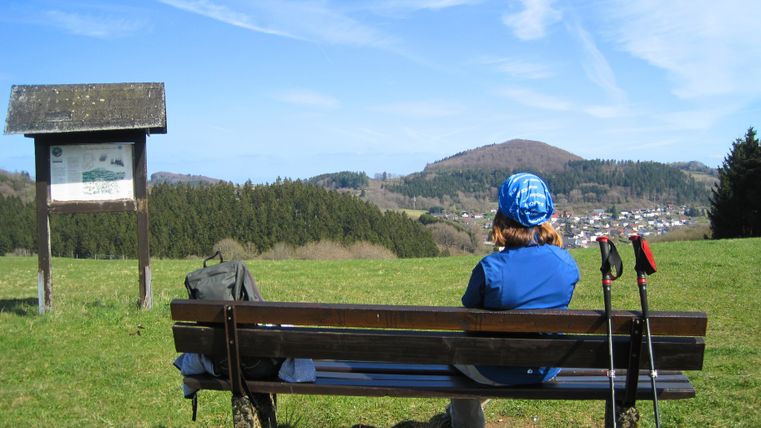 Persoon zittend op een bankje met uitzicht op de Nerother Kopf.