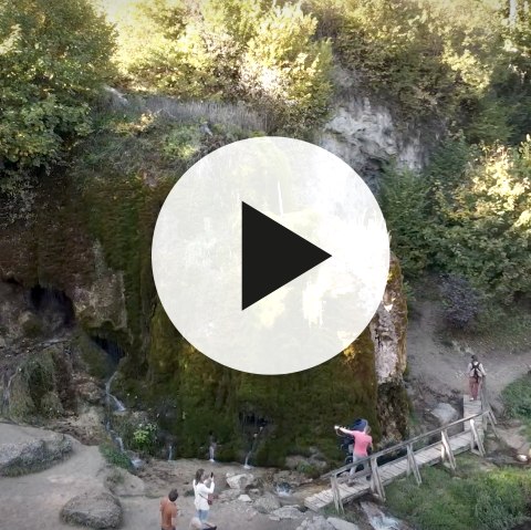 Aerial view of the growing Dreim&uuml;hlen waterfall with video play button in the foreground.