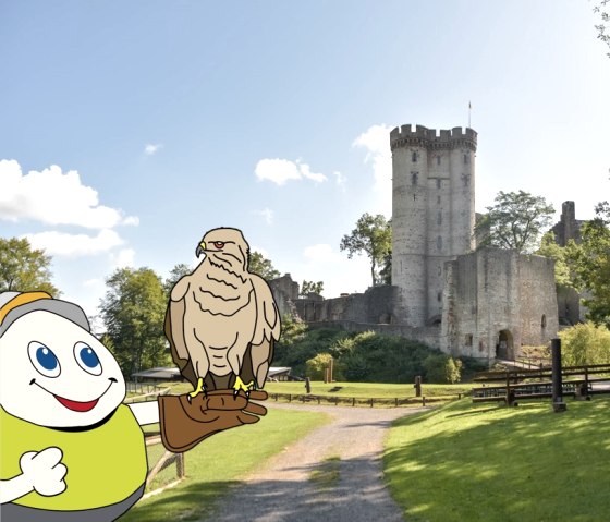 Cartoon character Willi Basalt in a green shirt stretches out his arm with an eagle perched on a falconer's glove. Behind him is the grounds of the Eagle and Wolf Park with Kasselburg Castle in Pelm.