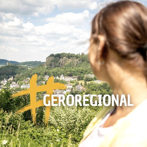 Eine Frau im Vordergrund schaut auf die Stadt Gerolstein. Davor ein Schriftzug &quot;#GEROREGIONAL&quot;.