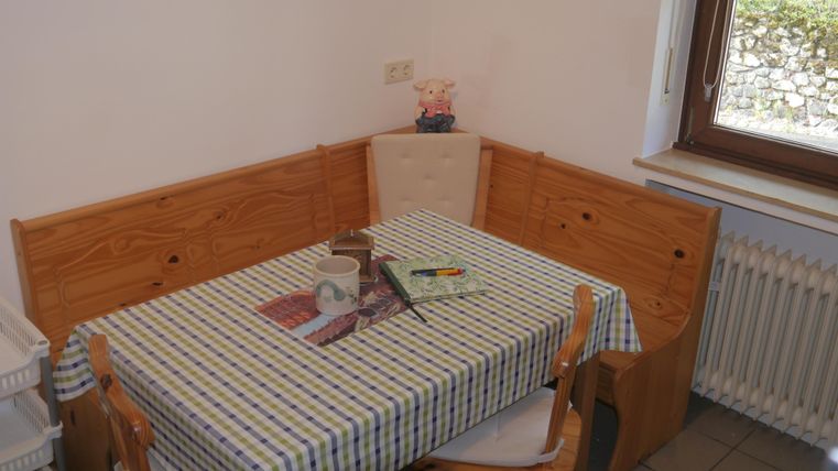 Ein kleiner Essbereich mit einem Holztisch und Stühlen. Der Tisch ist mit einer karierten Tischdecke gedeckt und es stehen einige Gegenstände darauf.