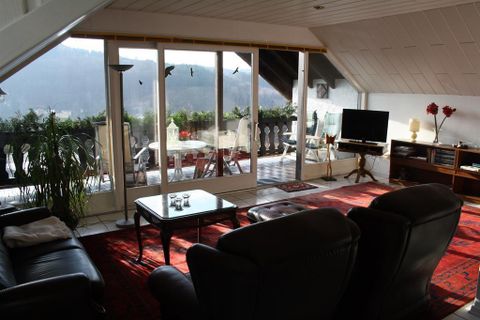 Ein gemütliches Wohnzimmer mit Ledermöbeln und einem großen Fenster, das auf einen Balkon mit schöner Aussicht führt. Die Einrichtung ist einfach und einladend.