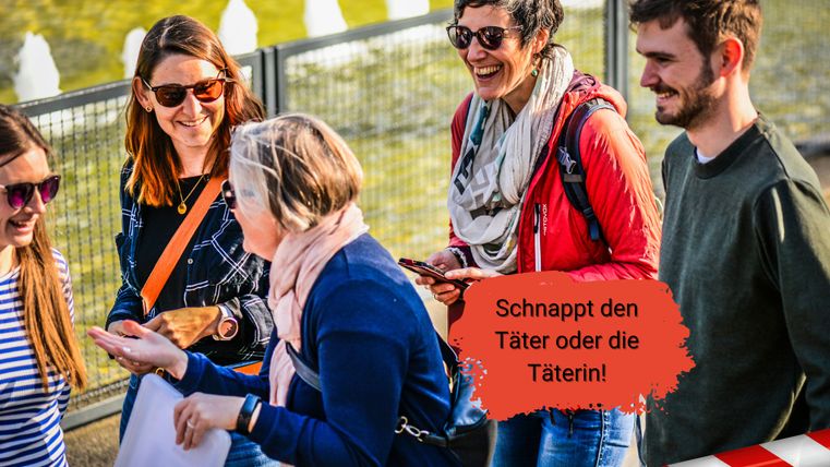 Eine Gruppe von Menschen lacht und diskutiert im Freien während einer Krimi-Tour.