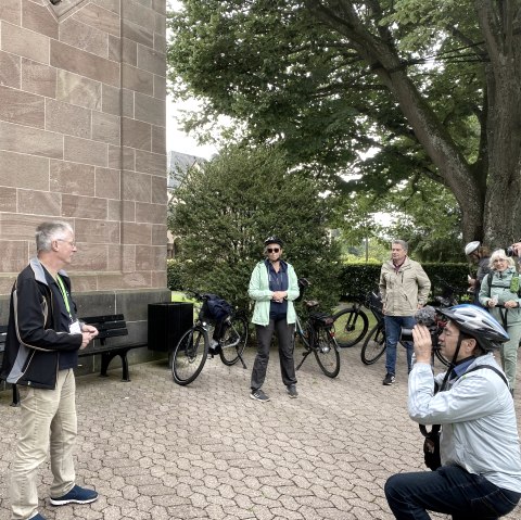 Mehrere Personen vor einem Gebäude. Einige halten Kameras auf einen Mann gerichtet.