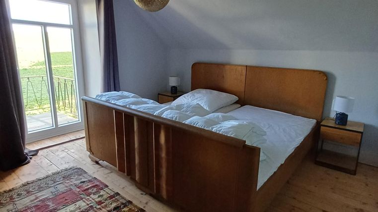 Een gezellige slaapkamer met een houten bed en een kleurrijk tapijt. Er zijn ramen met uitzicht naar buiten en een aangename verlichting.