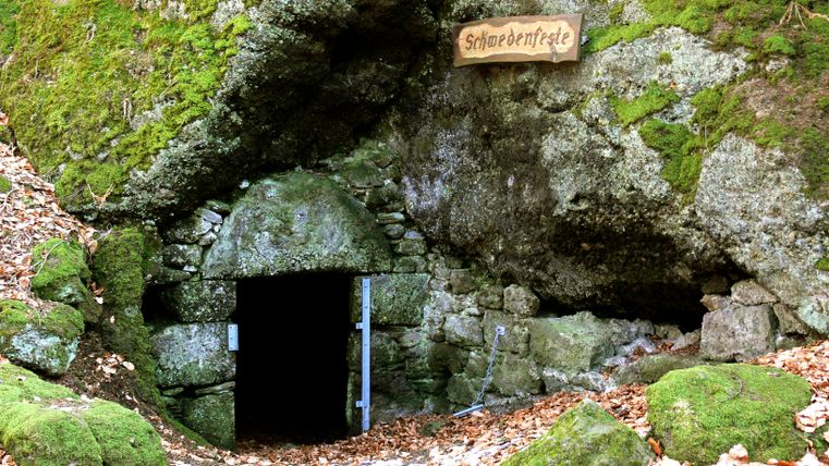 Eingang zur Schwedenfeste in einem moosbedeckten Felsen.