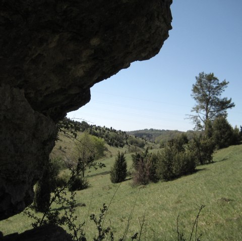 Rocky outcrop in the foreground, green hilly landscape with trees and blue sky in the background., © Touristik GmbH Gerolsteiner Land