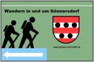 Bord met twee wandelaars, het wapen van G&ouml;nnersdorf en een blauwe pijl. Tekst: "Wandelen in en rond G&ouml;nnersdorf" en website-adres., &copy; Touristik GmbH Gerolsteiner Land