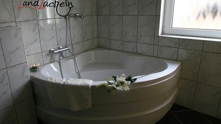 Ein modernes Badezimmer mit einer eleganten, freistehenden Badewanne. Der Raum ist hell und freundlich gestaltet, mit Fliesen und einem Fenster.