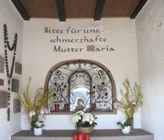 Kleine kapel met bloemen, kaarsen en de woorden 'Bid voor ons, bedroefde Moeder Maria' op de muur., © Touristik GmbH Gerolsteiner Land, Ute Klinkhammer