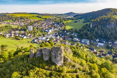 Luftaufnahme vom Auberg, Teil der Gerolsteienr Dolomiten, auf einem grün bewachsenen Berg oberhalb der Stadt Gerolstein.