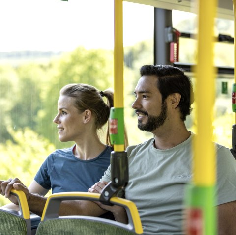 Een man en een vrouw zitten naast elkaar in een bus en kijken allebei uit het raam naar het landschap.