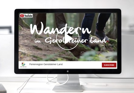 A computer screen on a table showing a YouTube video entitled &lsquo;Hiking in the Gerolsteiner Land&rsquo;.