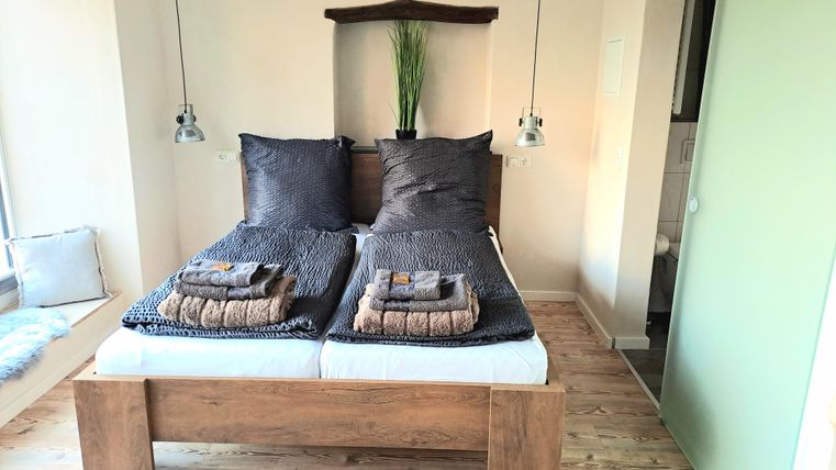 Ein modernes Schlafzimmer mit zwei Betten und stilvollen Kissen. Die Holzdetails und die sanfte Beleuchtung schaffen eine gemütliche Atmosphäre.