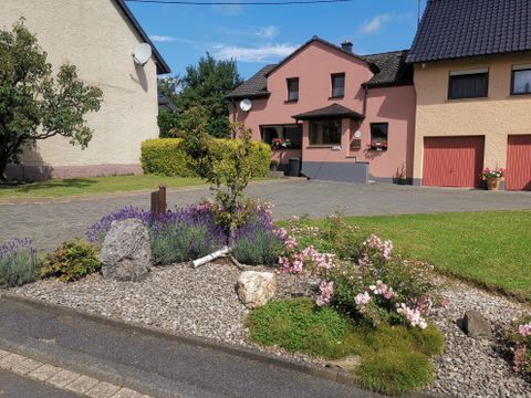 Ein schönes Wohnhaus mit einem gepflegten Garten. Bunte Blumen und Sträucher sind um den Eingang angeordnet.