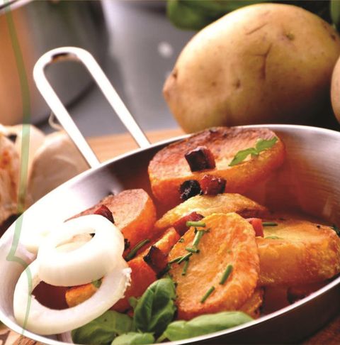 Gebratene Kartoffelscheiben mit Zwiebeln und Kräutern in einer Pfanne.