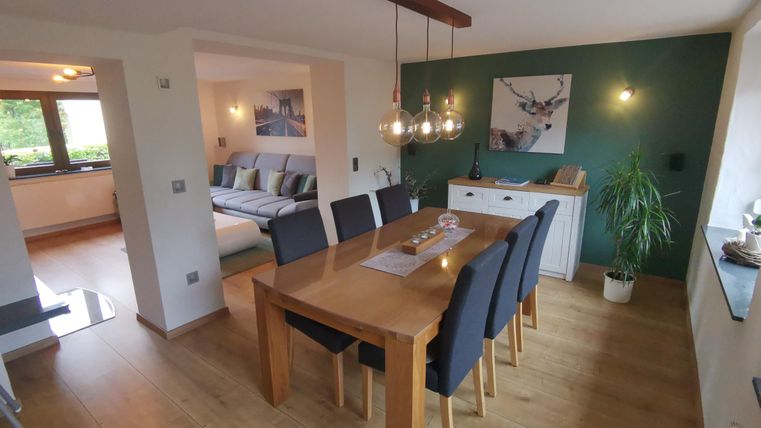 Une salle à manger moderne avec un bureau en bois et des chaises noires. Les murs sont peints dans des couleurs douces et il y a une décoration attrayante.