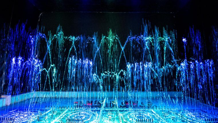 Wasserspielorgel mit blauen und grünen Lichtern in einem dunklen Raum.