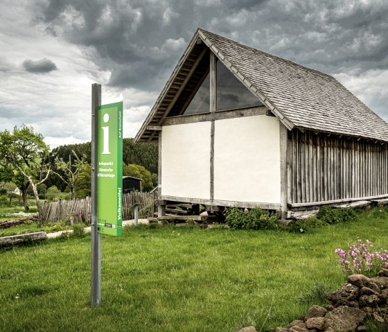 Ein gr&uuml;nes Informationsschild vor einem historischen Holzgeb&auml;ude in einer gr&uuml;nen Landschaft mit bew&ouml;lktem Himmel., &copy; Eifel Tourismus GmbH, Dominik Ketz