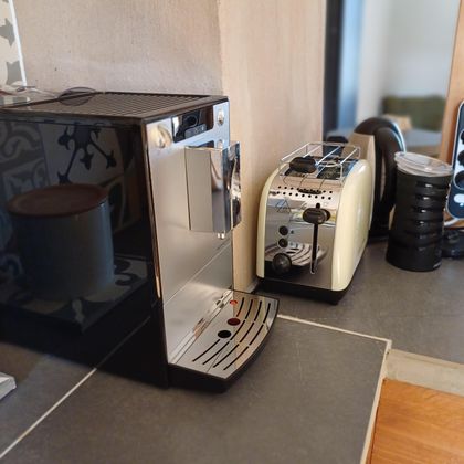 Een moderne keukenhoek met een koffiemachine en een toaster. De apparaten zijn op een donker aanrecht geplaatst.