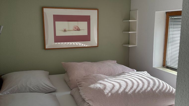 Ein gemütliches Schlafzimmer mit einem großen Bett und hellen Bettdecken. Die Wände sind in sanften Farben gestrichen, und an der Wand hängt ein Bild.