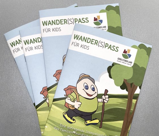 Mehrere Prospekte "Wander(S)pass f&uuml;r Kids" liegen aufeinander auf einem Tisch.
