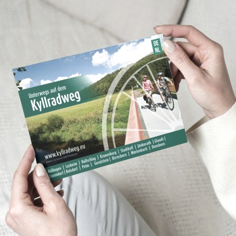 Der Flyer &quot;Unterwegs auf dem Kyllradweg&quot; wird hochgehalten.