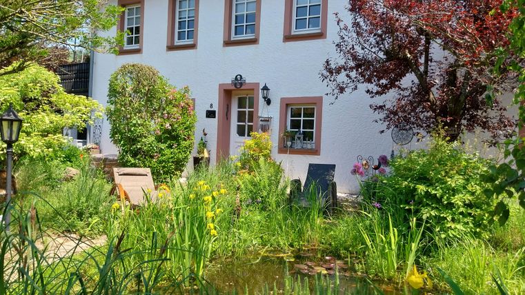 Een charmant huis met een mooie tuin. Kleurrijke bloemen en groen gras omringen de voordeur.