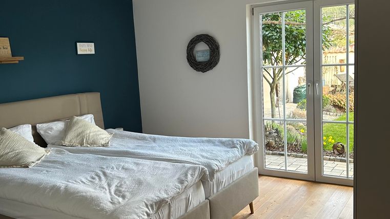 Une chambre moderne avec un lit double et une grande fenêtre donnant sur une vue de jardin. Les murs sont dans des tons doux.