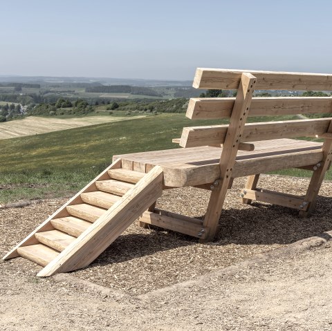 An oversized wooden bench stands on a hill overlooking a vast landscape., © Jochen Hank
