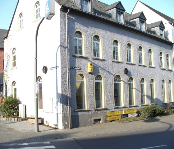 Au&szlig;enfassade der Tourist-Information Hillesheim mit Deutscher Post Filale und DHL Shop.