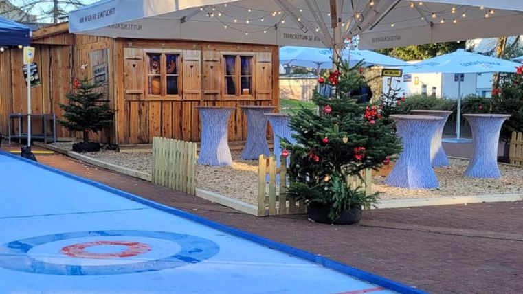 Kleine Boccia-Eisbahn, im Hintergrund Stehtische und Holzhütte mit weihnachtlicher Dekoration