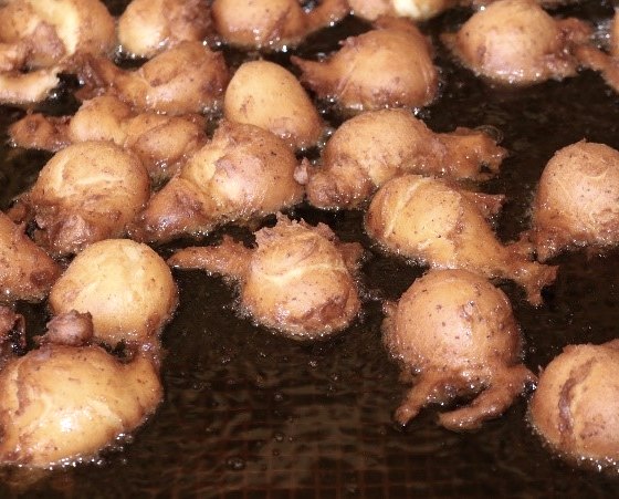 Nahaufnahme von zahlreichen Teigbällchen, die im Fett gebacken werden.