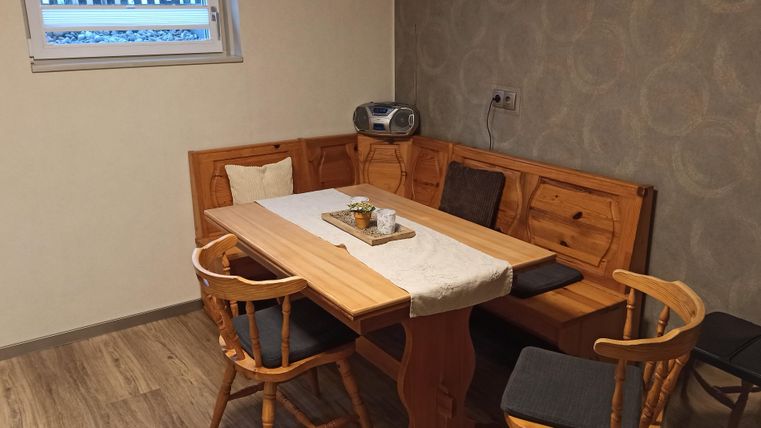 Un coin repas confortable avec une table en bois et des chaises.
Il y a une fenêtre sur le mur, et la décoration est simple et moderne.