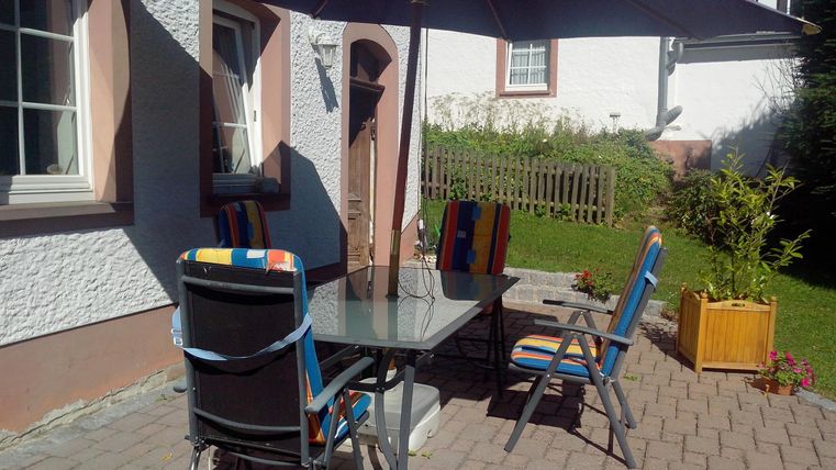 Ein gemütlicher Außenbereich mit einem Tisch und Stühlen unter einem großen Sonnenschirm. Die Anlage ist gut gepflegt und lädt zum Entspannen ein.