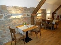 Een gezellig restaurant met houten stoelen en tafels. De muren zijn van steen en de verlichting zorgt voor een warme sfeer.