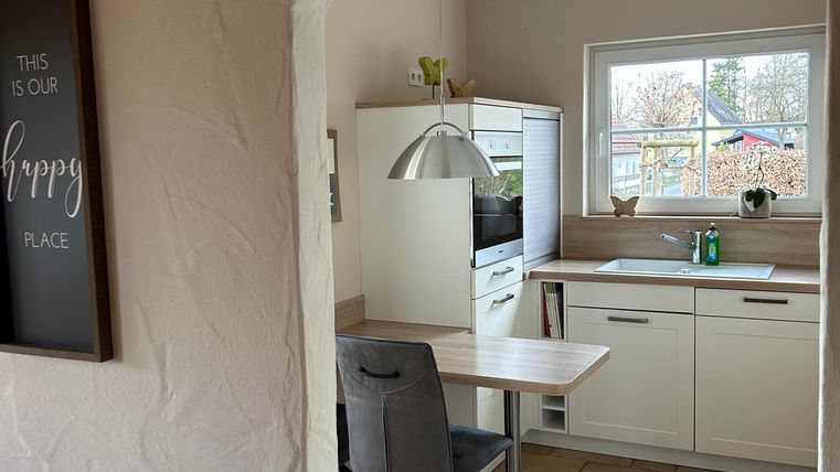 Une cuisine lumineuse avec une grande fenêtre et des meubles modernes.
La pièce est visible à travers une voûte et semble accueillante.