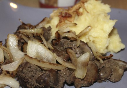 Fleisch- und Zwiebelzubereitung mit einem Haufen Kartoffelpürree daneben.