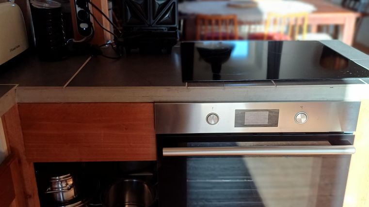 Een moderne keuken met een glanzend fornuis en een ingebouwde oven. De ruimte lijkt helder en uitnodigend.