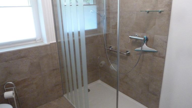 A modern bathroom with a glass shower. The wall tiles are in a light color tone, creating an inviting atmosphere.
