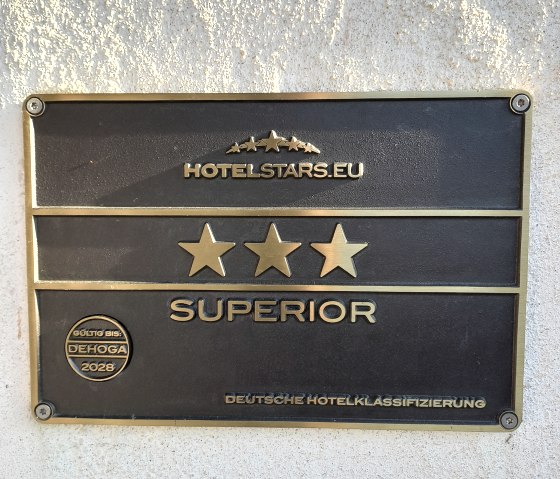 Eine Stahlplakette an einer Auswand von hotelstars.eu mit den verdienten 3 Sternen und dem Zusatz Superior. G&uuml;ltig bis 2028. 