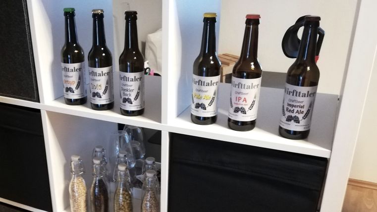 Ein weißes Regal, in dem in mehreren Fächern Bierflaschen unterschiedlicher Sorten der Marke "Wirfttaler" stehen.