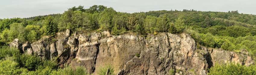 Rocky volcanic wall in a green landscape.