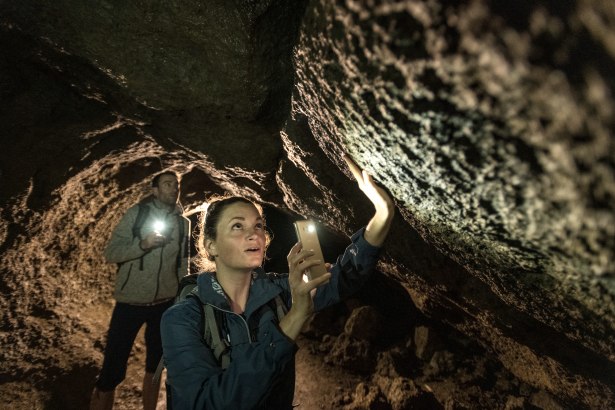 Zwei Personen in einer Höhle, die mit Taschenlampen die Wände erkunden. Die Szene ist in warmes Licht getaucht., © Eifel Tourismus GmbH, Dominik Ketz