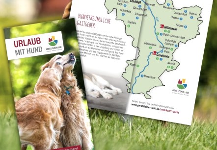Voorpagina van de brochure &ldquo;Vakantie met hond&rdquo; met geopende pagina's die een overzichtskaart van de regio tonen.