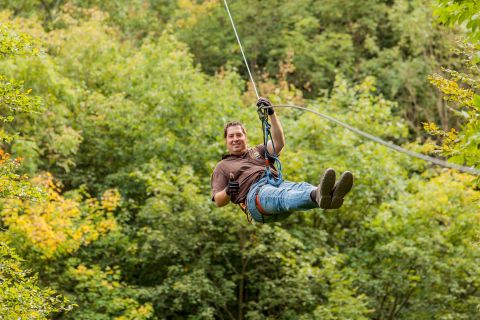 Mann, der an einer Zipline im Wald hängt